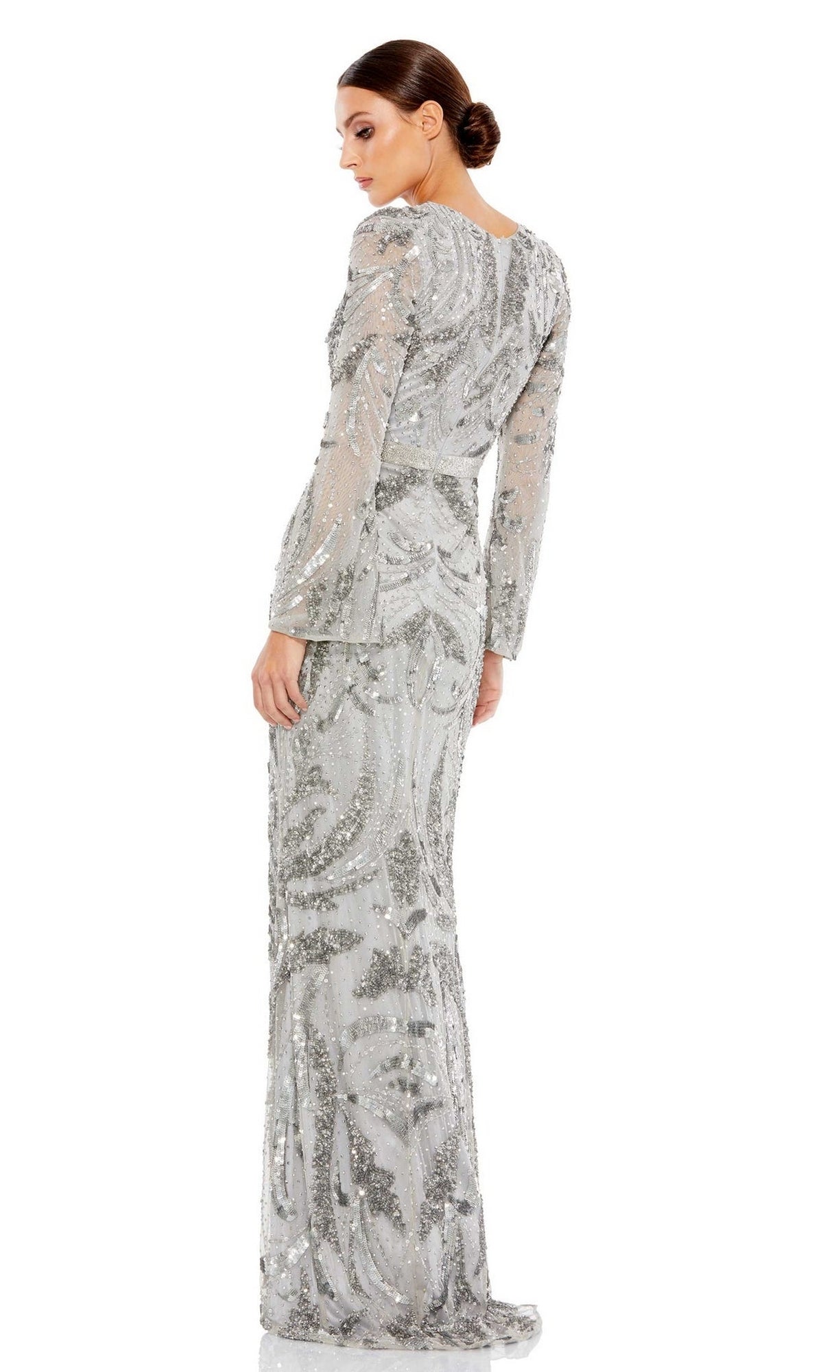 A woman stands against a white background, looking over her shoulder in the Long Formal Dress 5222 by Mac Duggal, featuring silver beading, long sleeves, and a fitted waist.